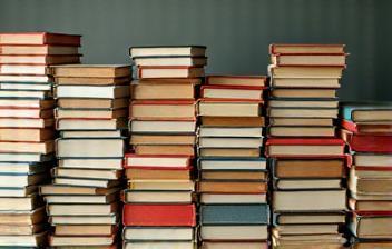 Stacks of new books with vibrant covers next to piles of older, used books